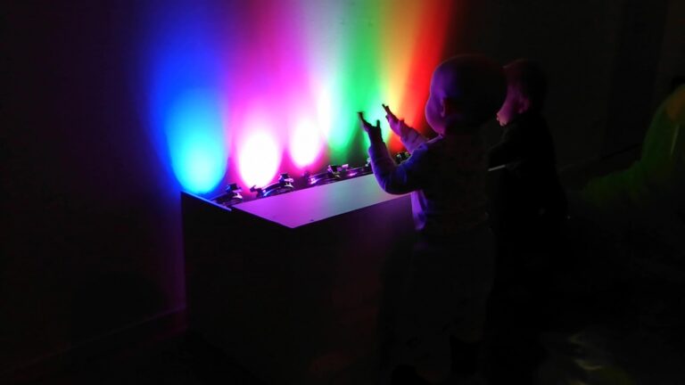 Vauvojen värikylpy -työpajassa vauva katsoo värivalojen vaihtumista ja taputtaa.