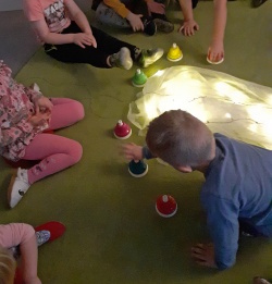 Lapsia ringissä lattialla, kasvot eivät näy, keskellä valoja ja värikkäitä painikkeita, lapset leikkivät.