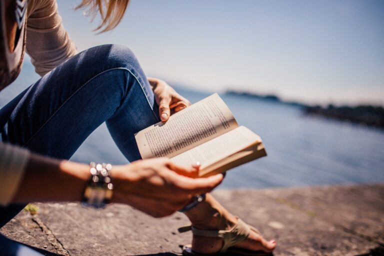 Tyttö lukemassa kirjaa rantakalliolla