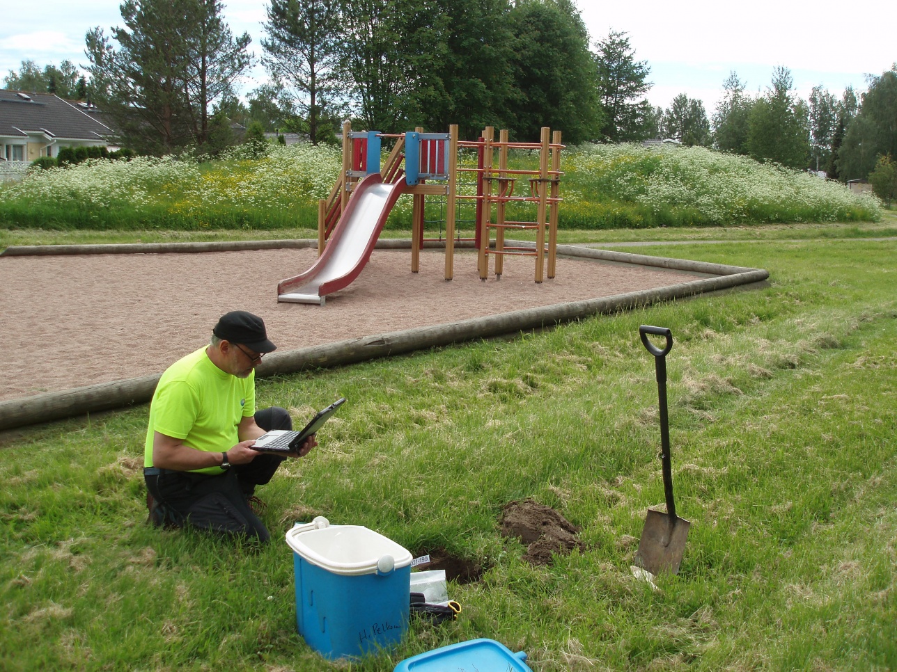 Mies leikkipuiston nurmikentällä mittaamassa maaperää 