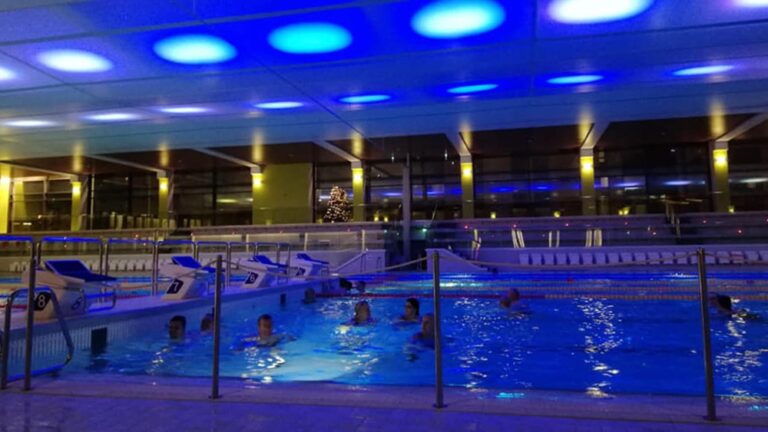 Hämärästi valaistu keskustan uimahalli, jossa on uimareita