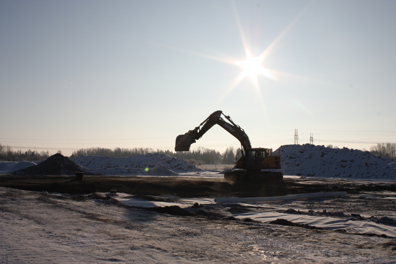 Traktori lumihangessa ja taustalla paistaa aurinko