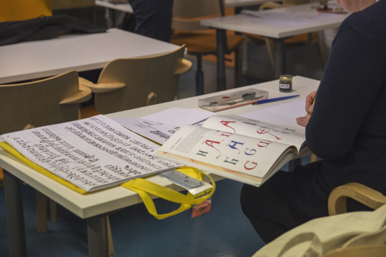 Opiskelija tekee kalligrafian tehtäviä