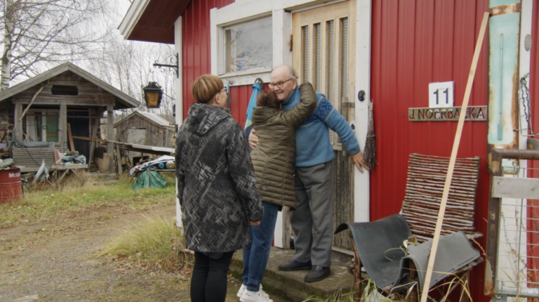 Kaksi naista seisoo ulkona, joista toinen halaa vanhaa miestä Tervetuloa kotiin -ohjelmasarjassa