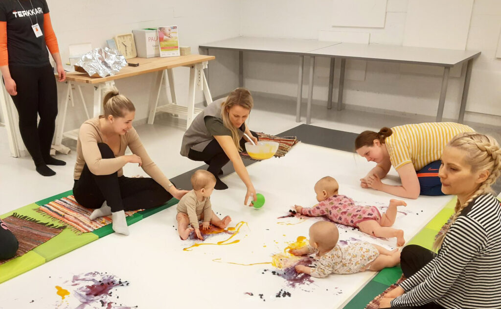 Three babies and their parents are in the Experiential Colour Workshop for Babies.