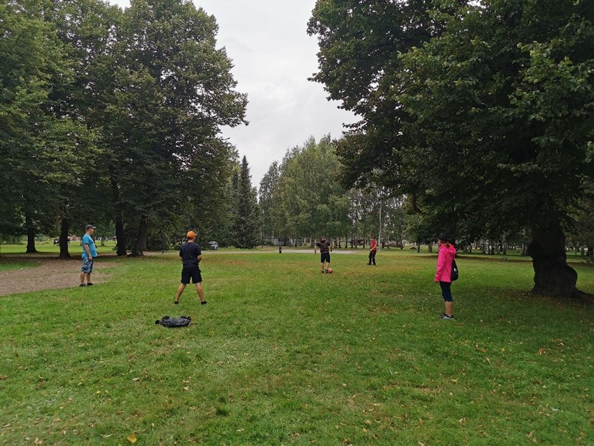 Joukko ihmisiä pelaa jalkapalloa puistossa.