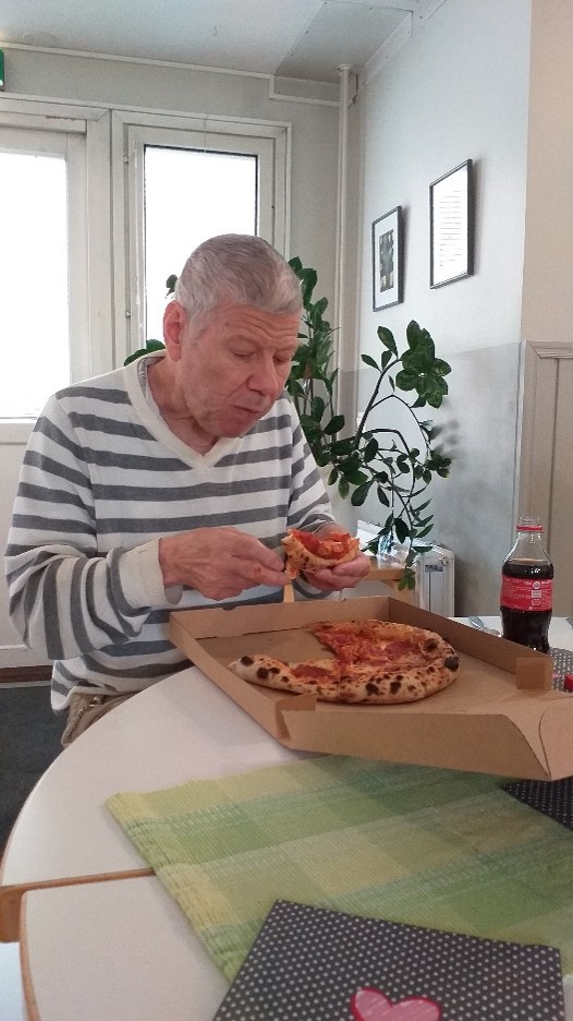 Mies raitapaidassa syö pitsaa.
