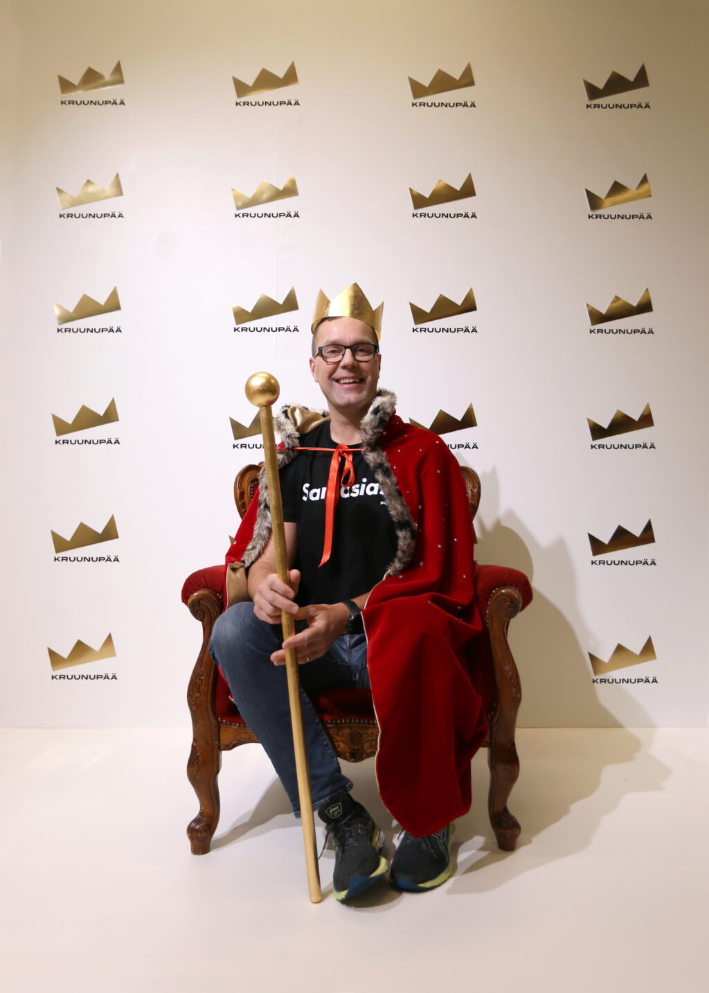 Kaupunginjohtajalla on asusteinaan kultainen kruunu ja valtikka sekä viitta. Taustalla on kultaisia Kruunupään logoja.