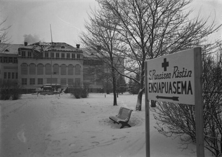Mustavalkoinen kuva Cygnaeuksen koululta jossa kyltti Suomen Punaisen Ristin ensiapuasema