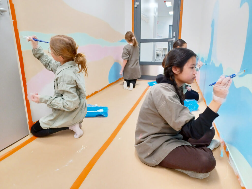 Koulun oppilaita maalaamassa koulun odotustilaa