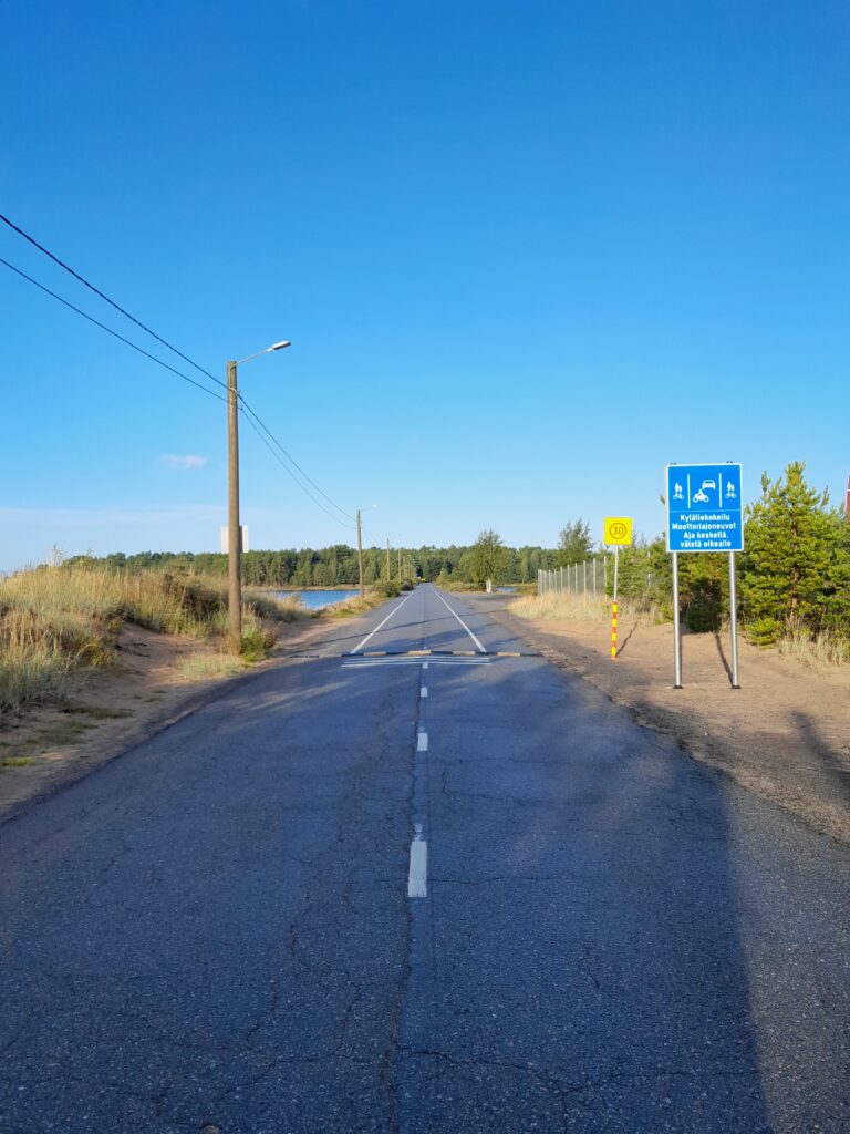 keskellä tie, jonka vieressä kylätiestä kertova liikennemerkki