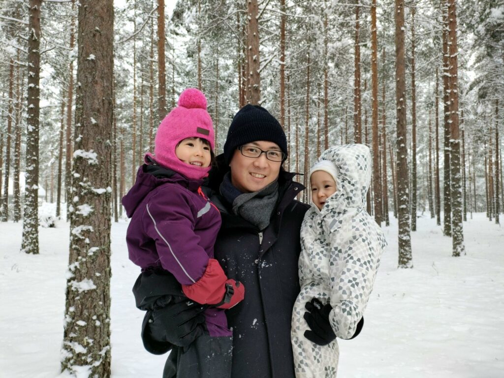 A man in a snowy forest with two small children