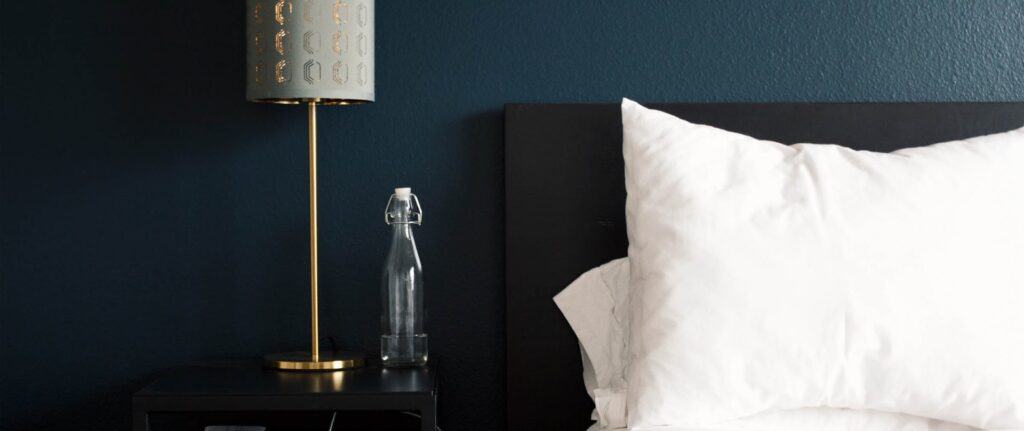 Lamp, water bottle, pillow and bed headboard