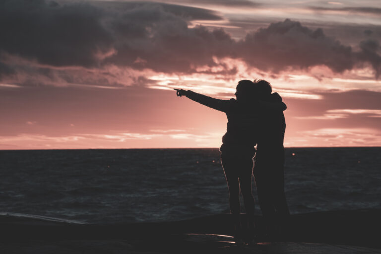 couple pointing to the horizon at sunset