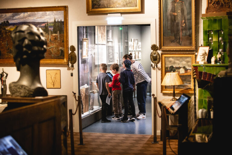 Nainen ja kolme lasta katsomassa vitriiniin Satakunnan museon näyttelyssä