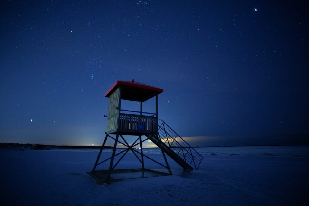 Rantavalvojan torni yöllisellä rannalla tähtitaivaan alla.