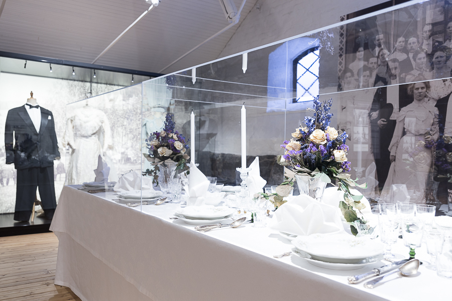 Ahlström Voyage -näyttelyä, juhlakatettu pöytä ja taustalla juhla-asut