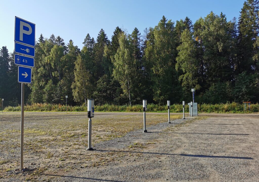 sähkötolppia hiekkakentällä, taustalla metsää