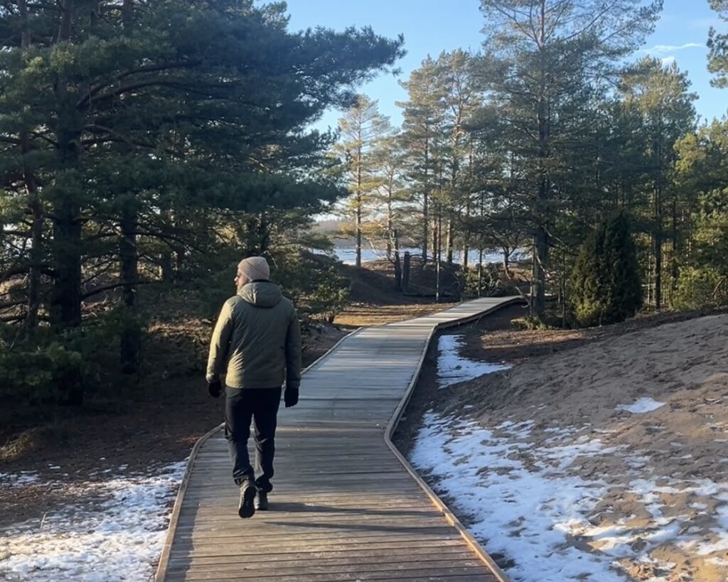 Mies kävelee puisella lankongilla Yyterin metsämaisemissa.