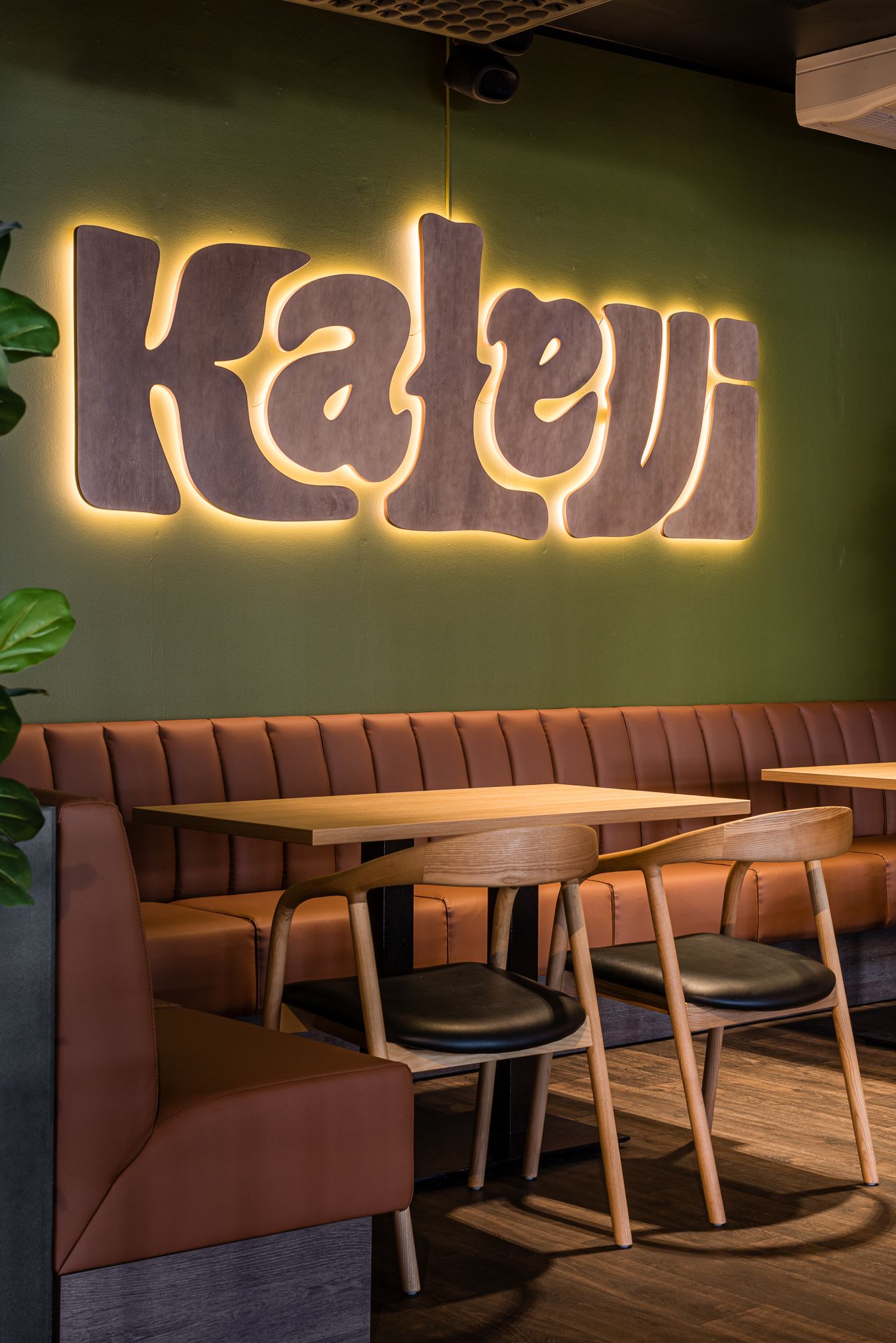 Kalevi Bar & Kitchenin logo valaistuna vihreällä seinällä.