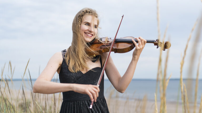 Johanna Ilvesmäki Yyterissä rannalla viulun kanssa.